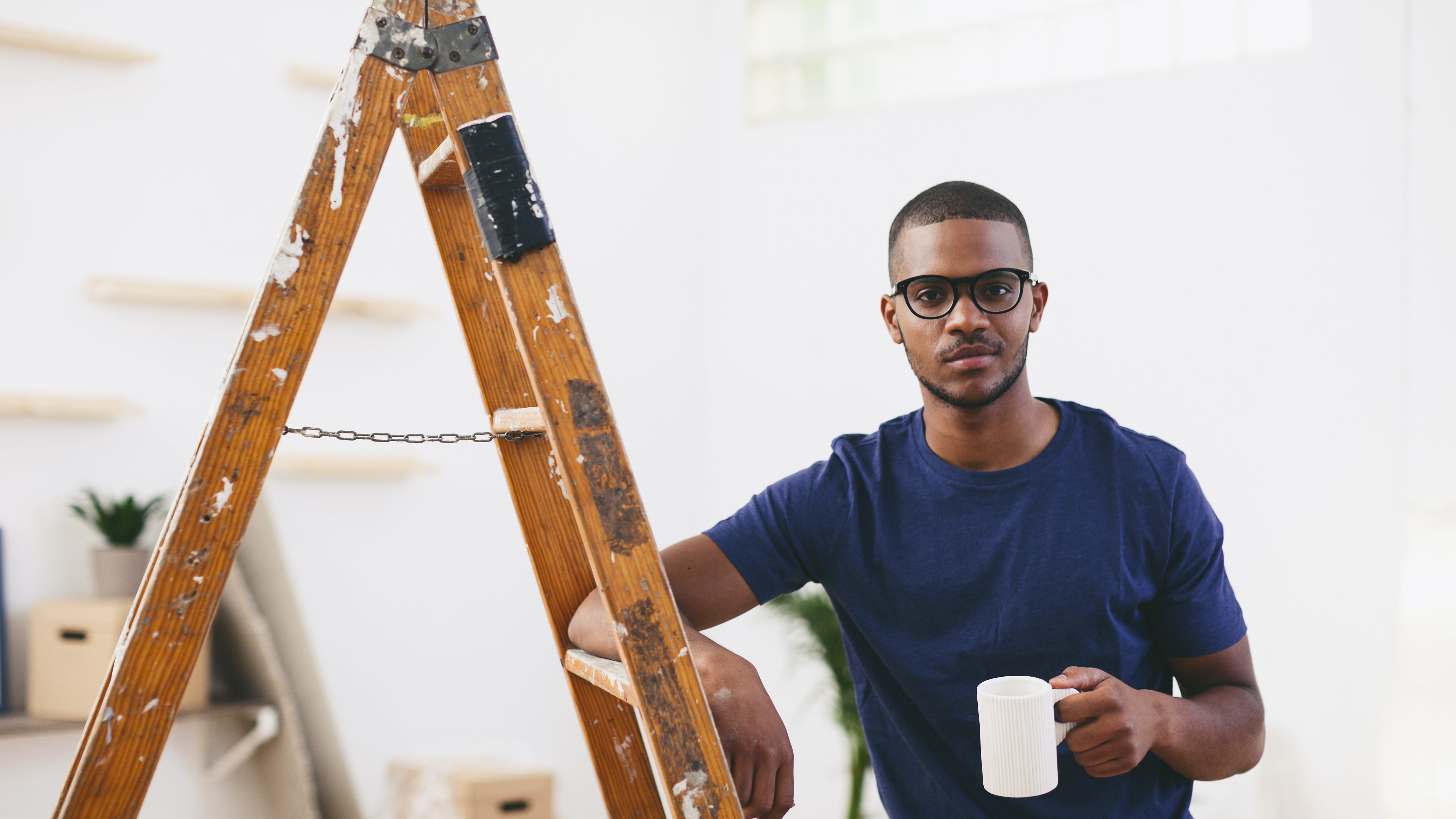 Young man leaning on step ladder having a coffee break