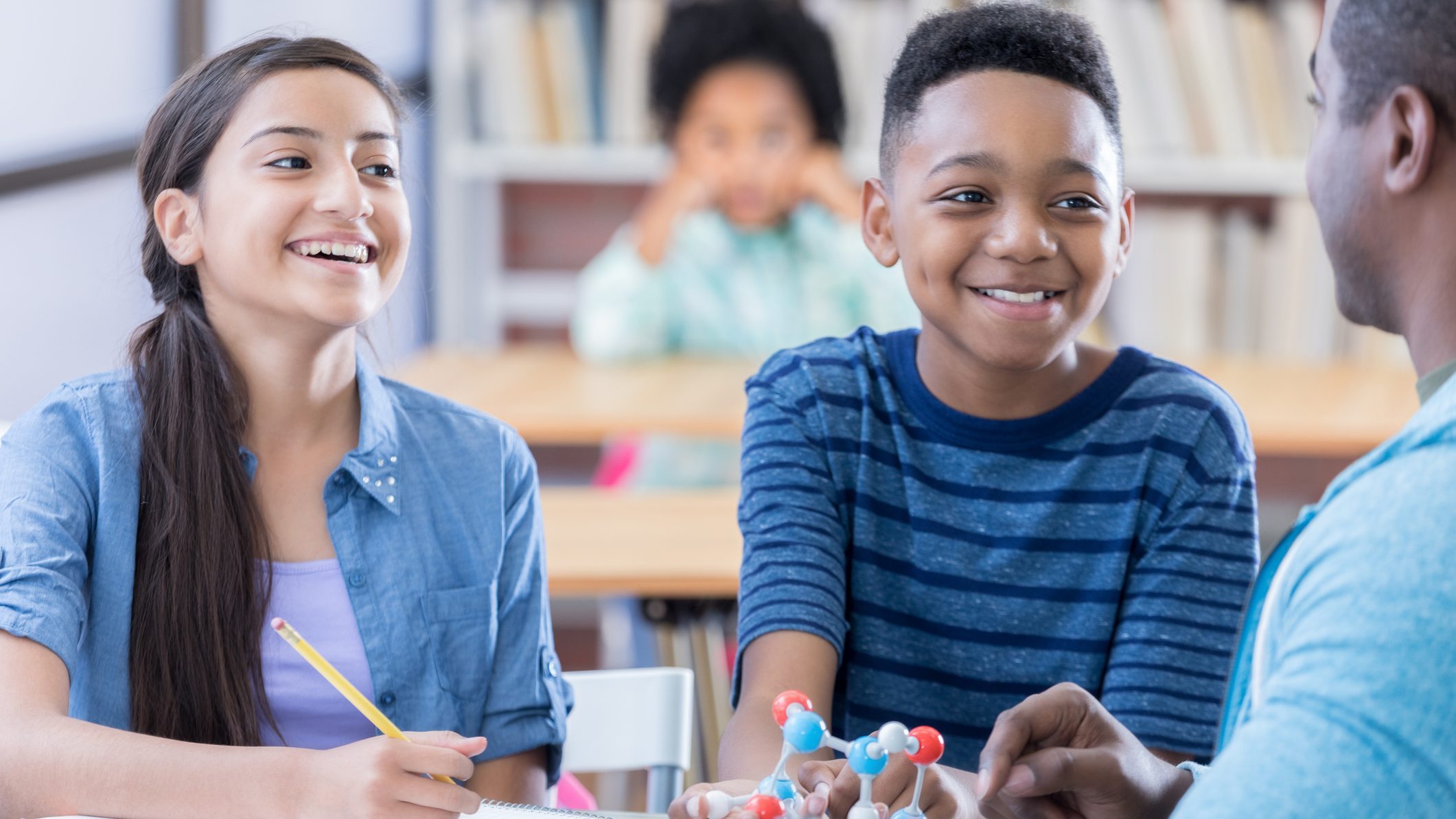 Two preteen students listen to Chemistry teacher define an atom