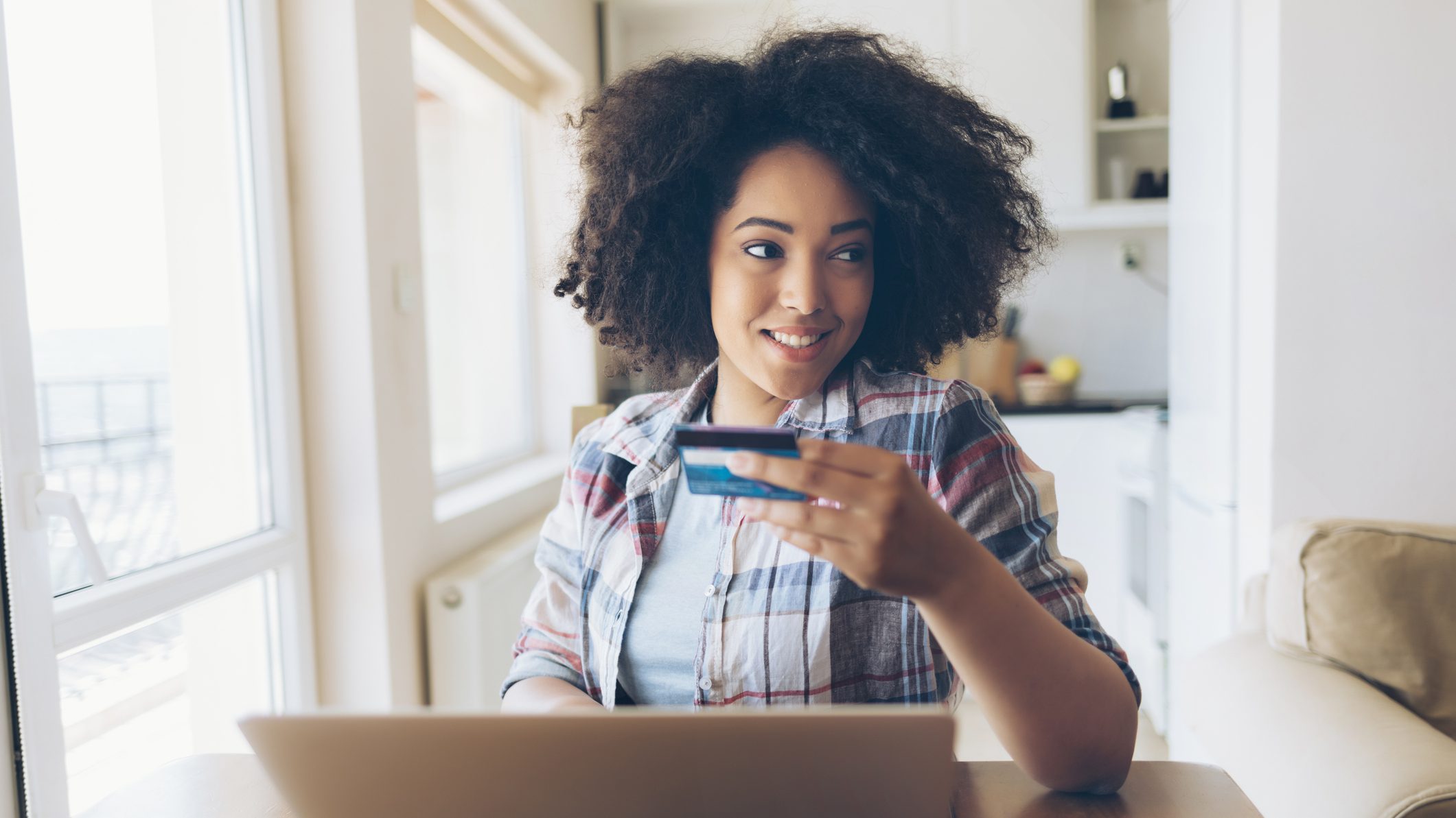 Woman using credit card and laptop at home